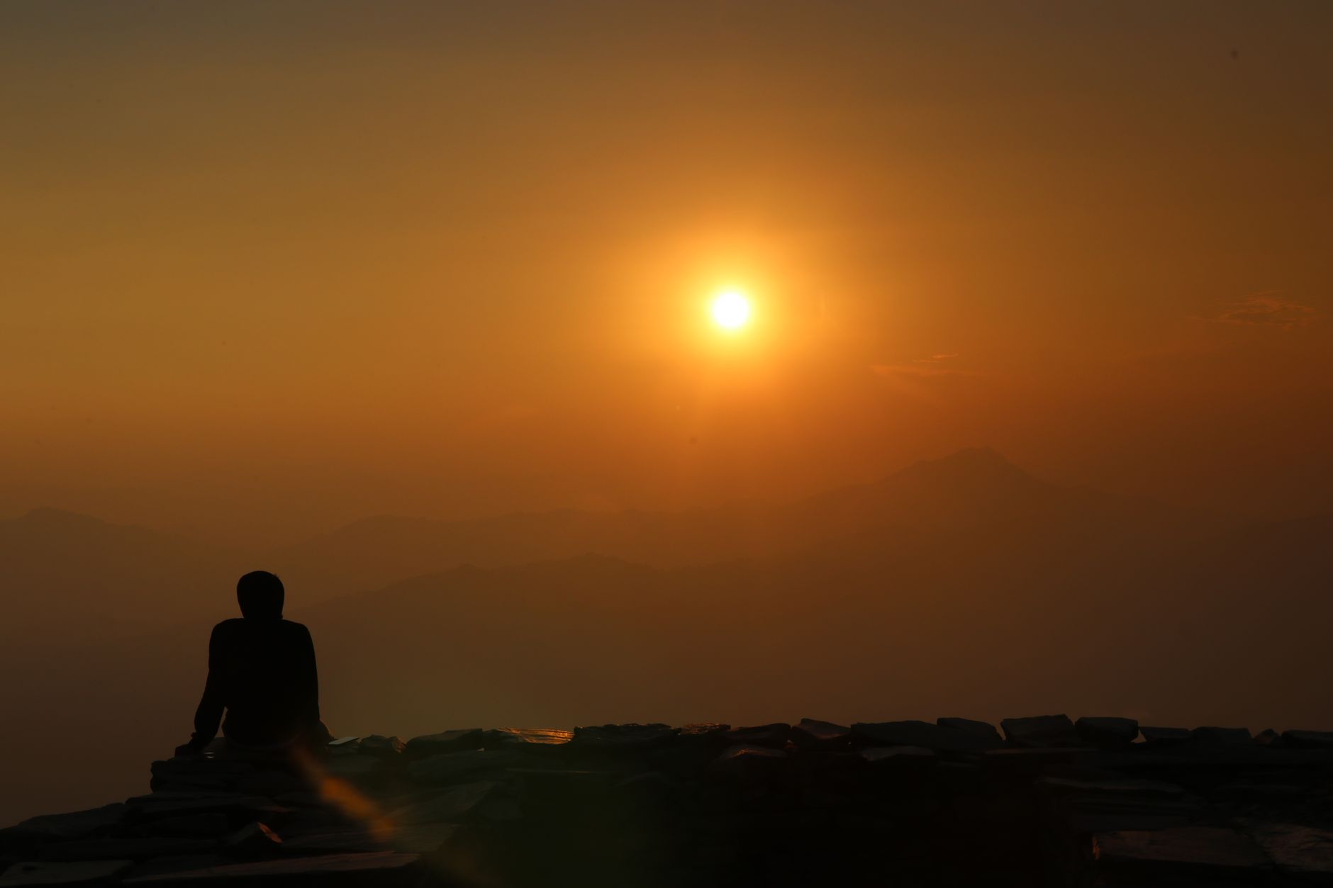 Meditierende Person als Silhouette im warmen Licht des Sonnenaufgangs