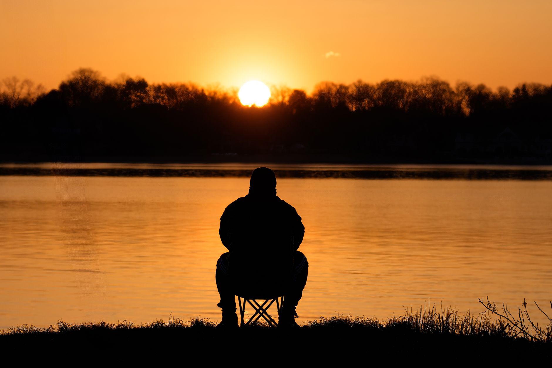 Meditierende Person am Wasser im Licht des Sonnenaufgangs